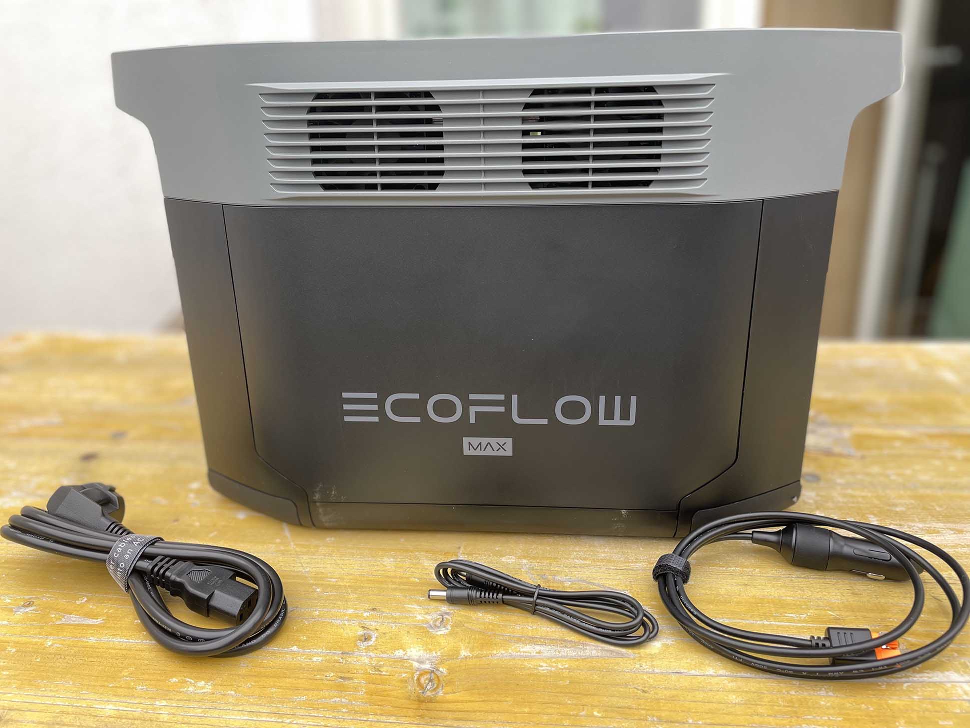 Der EcoFlow DELTA 2 Max Speicher steht auf einem Tisch und daneben liegen die wichtigen Kabel zur Verkabelung mit dem Wechselrichter oder Solarmodulen.